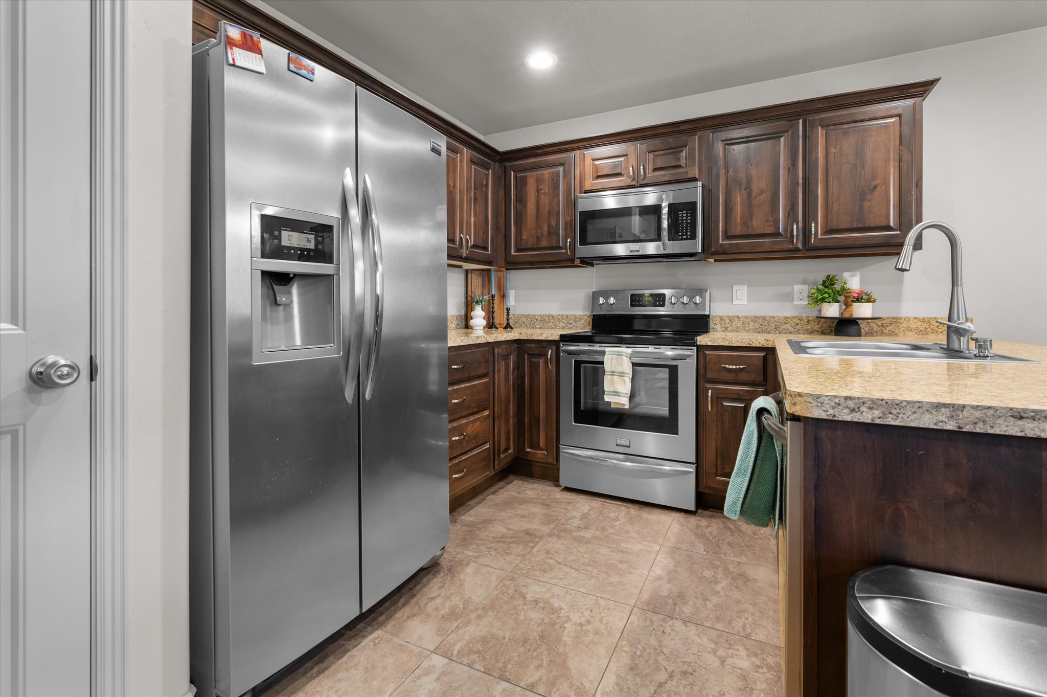 Kitchen featuring stainless steel appliances, wood cabinetry, laminate countertops, and tile flooring
