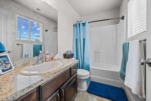 Bathroom featuring a vanity with an integrated sink, a speckled countertop, dark wood-finish cabinetry, and a full-width mirror