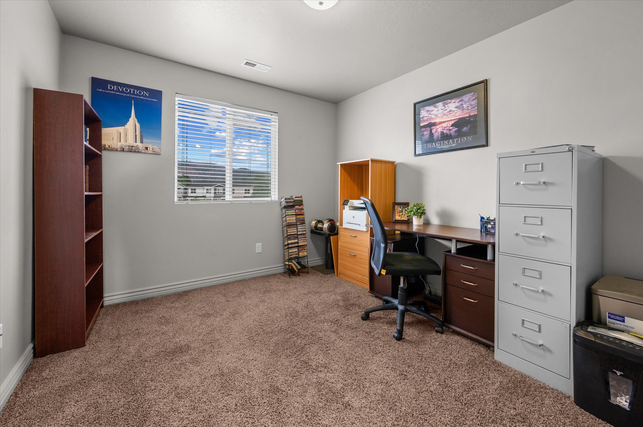 Carpeted room with a ceiling light fixture, a window featuring horizontal blinds, and neutral-toned wall paint