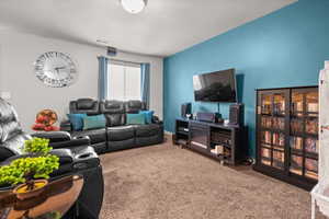 Living area featuring a textured carpet, a distinctive accent wall