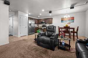 Open-concept living space featuring recessed lighting, a modern kitchen with dark wood cabinetry and stainless steel appliances, and a dedicated dining area with a chandelier
