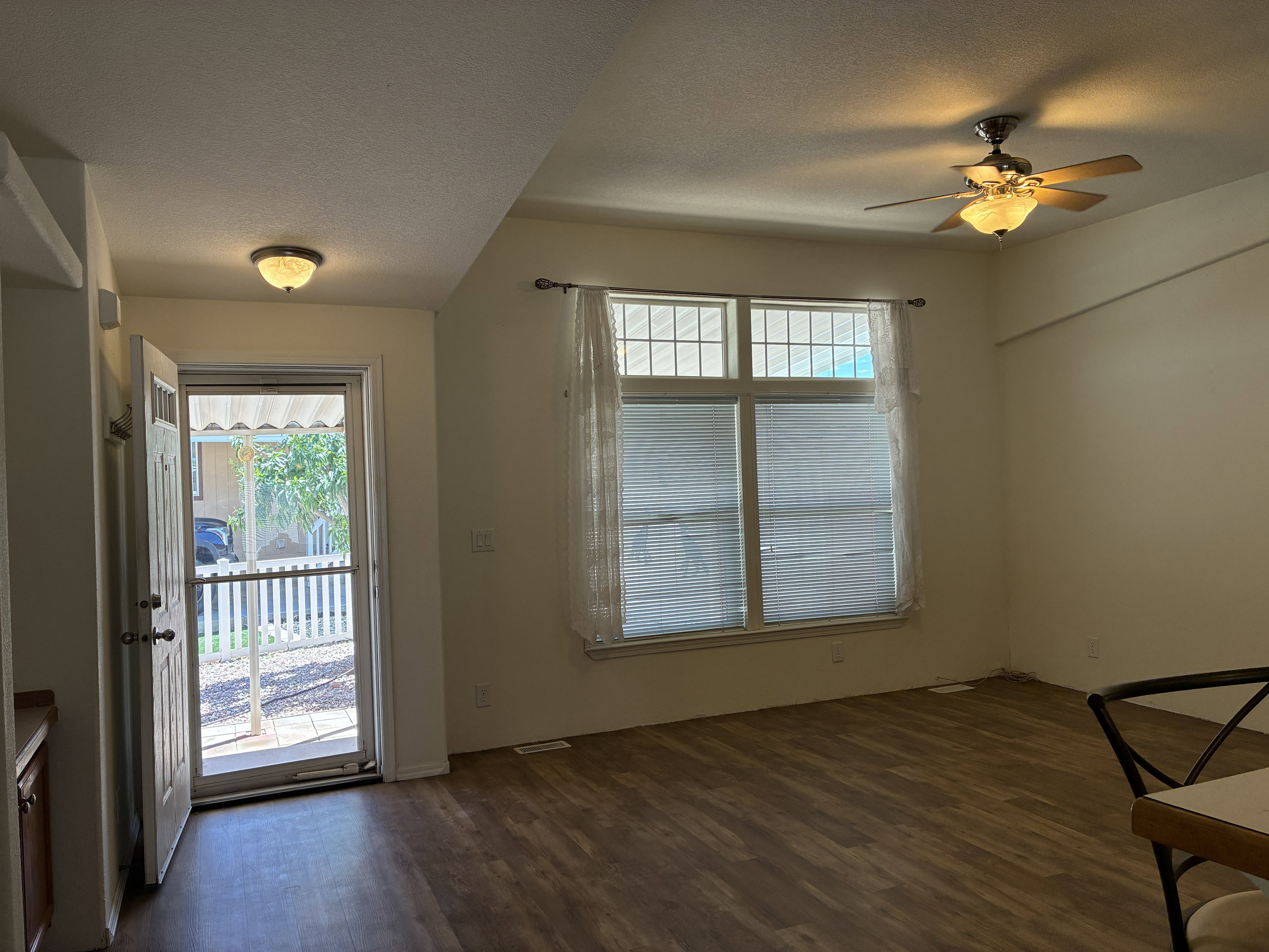 Spacious living area featuring LVP flooring, a multi-pane window with blinds, a storm door and a ceiling fan with integrated lighting