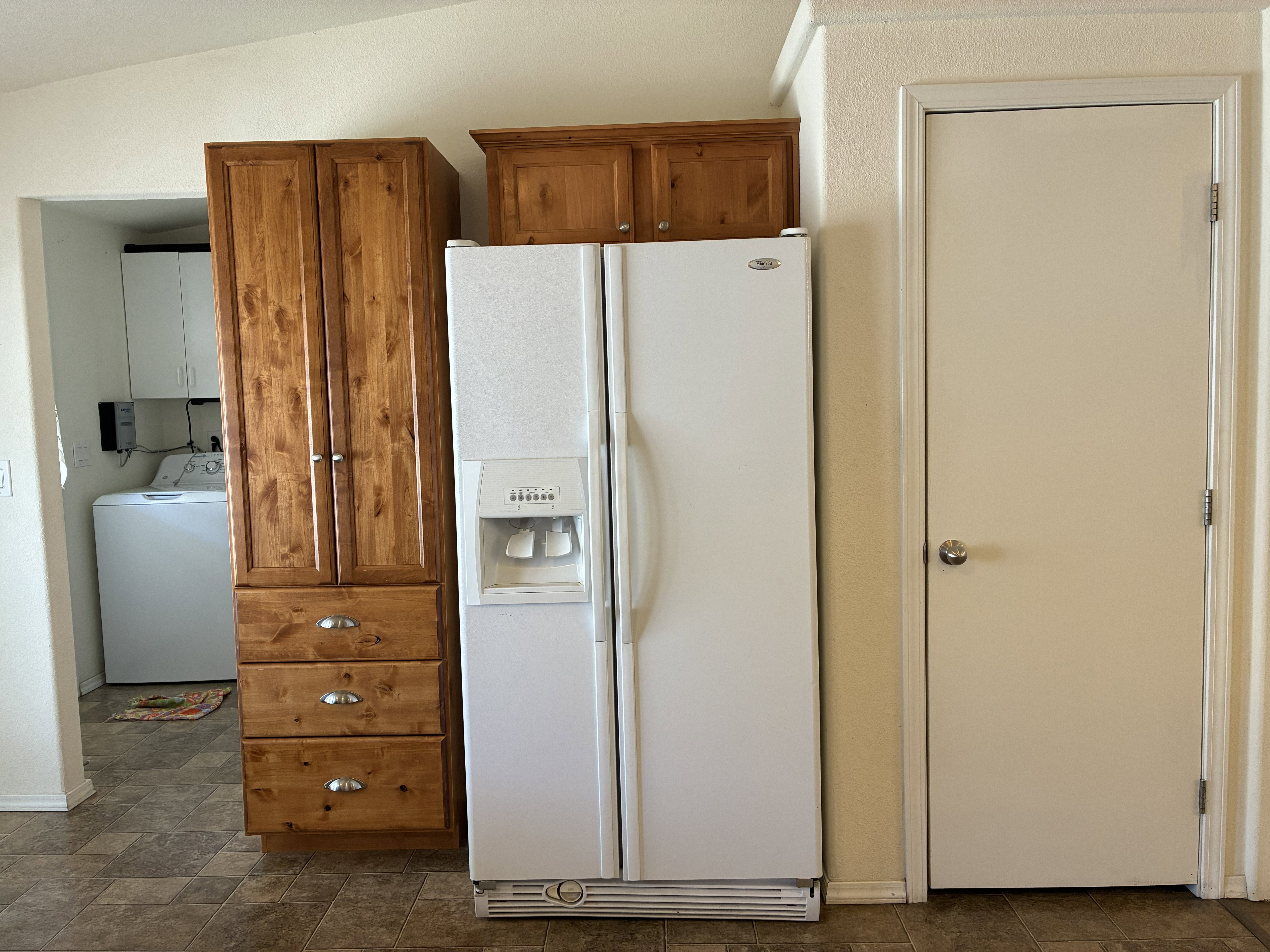 Kitchen area featuring wood-finish cabinetry with silver hardware and a pantry closet