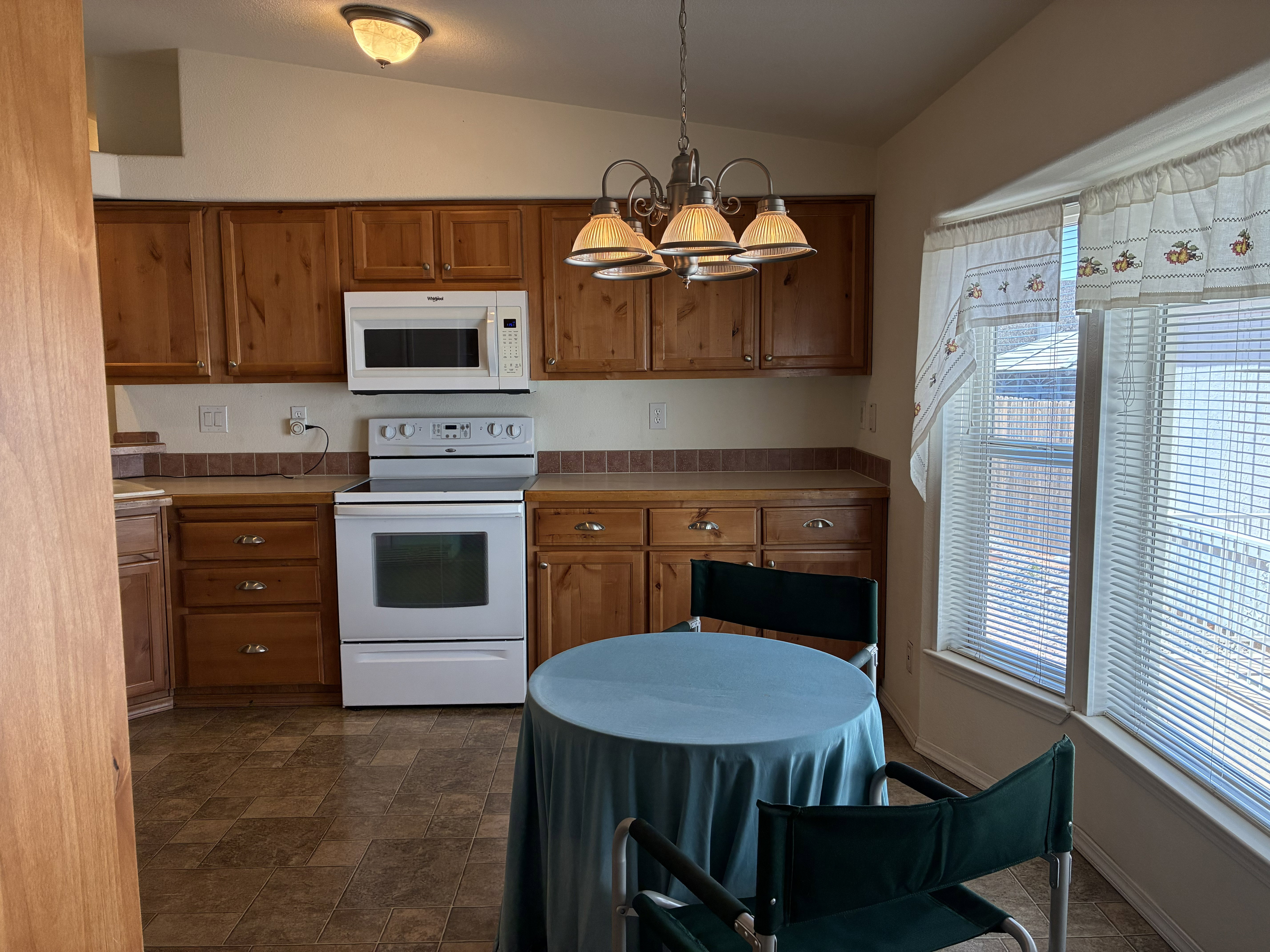 Dining and kitchen featuring wood cabinetry, white appliances, a tiled backsplash, and a bay window