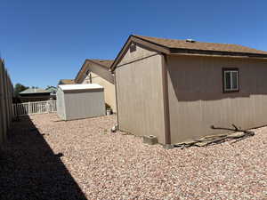 Expansive gravel yard featuring a workshop and storage shed, a white picket fence, and a gate