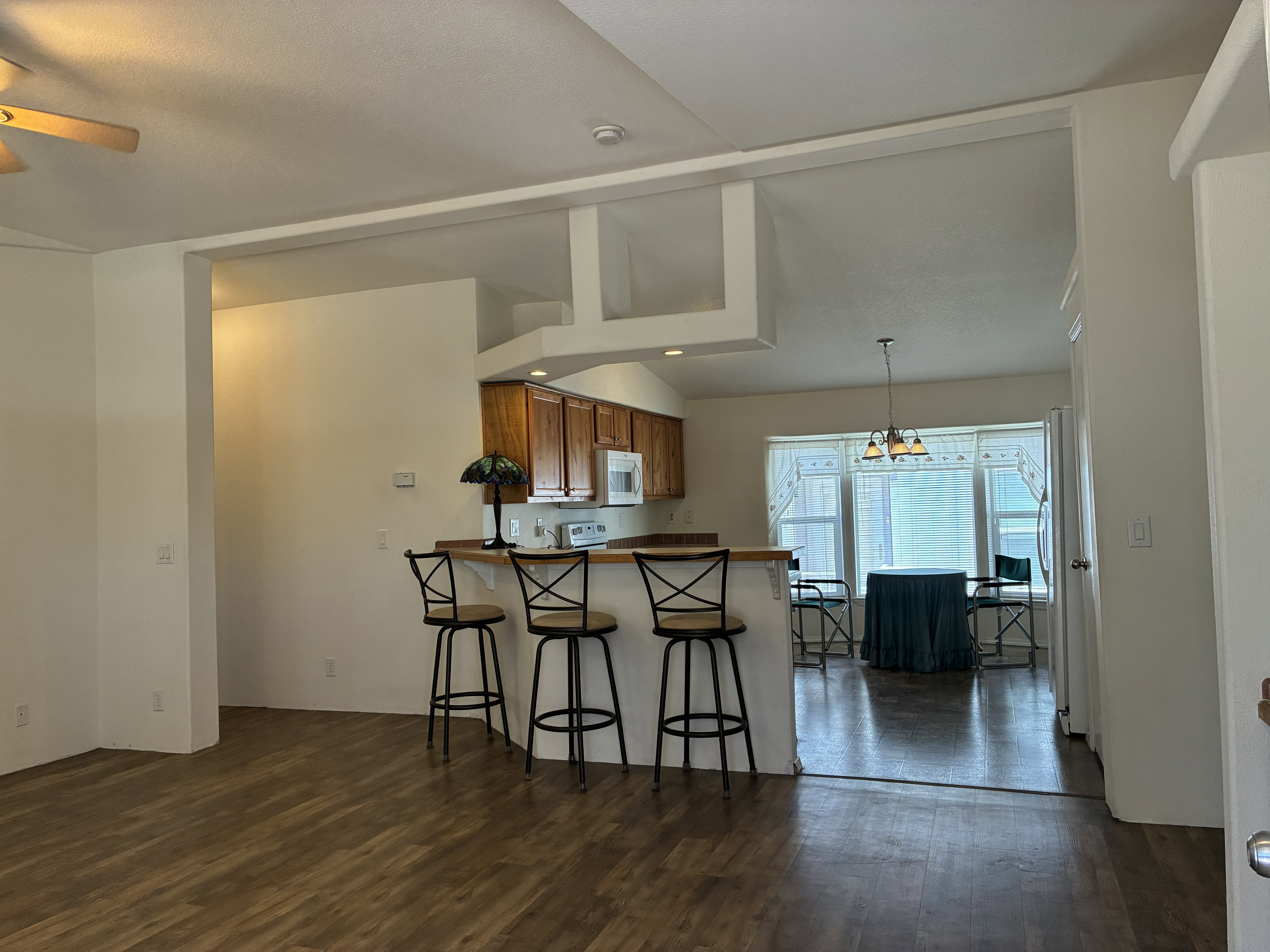 Open-concept living area with LVP flooring, a breakfast bar, plant shelves and vaulted ceilings
