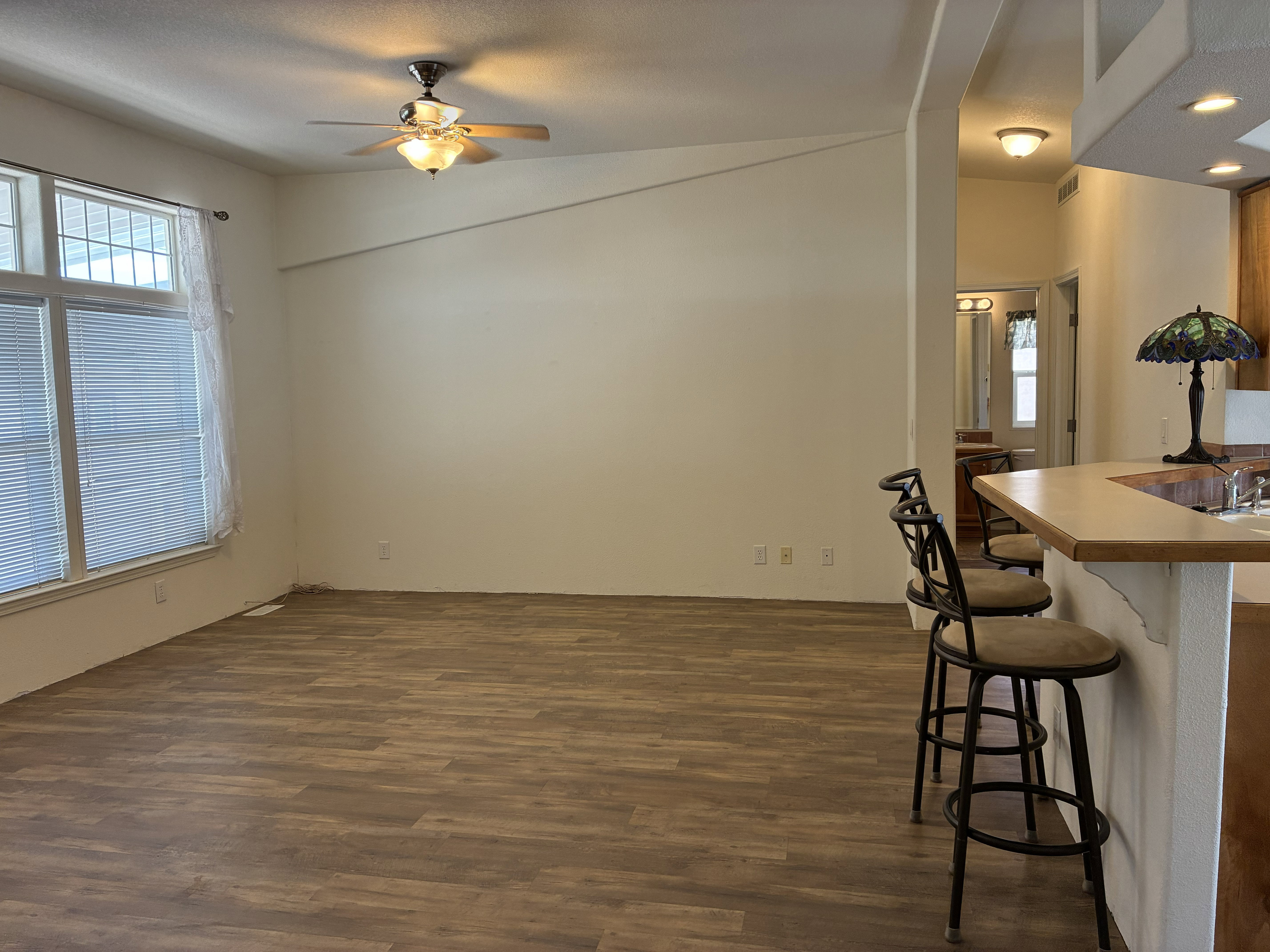 Spacious living area featuring LVP flooring, vaulted ceiling, and a ceiling fan