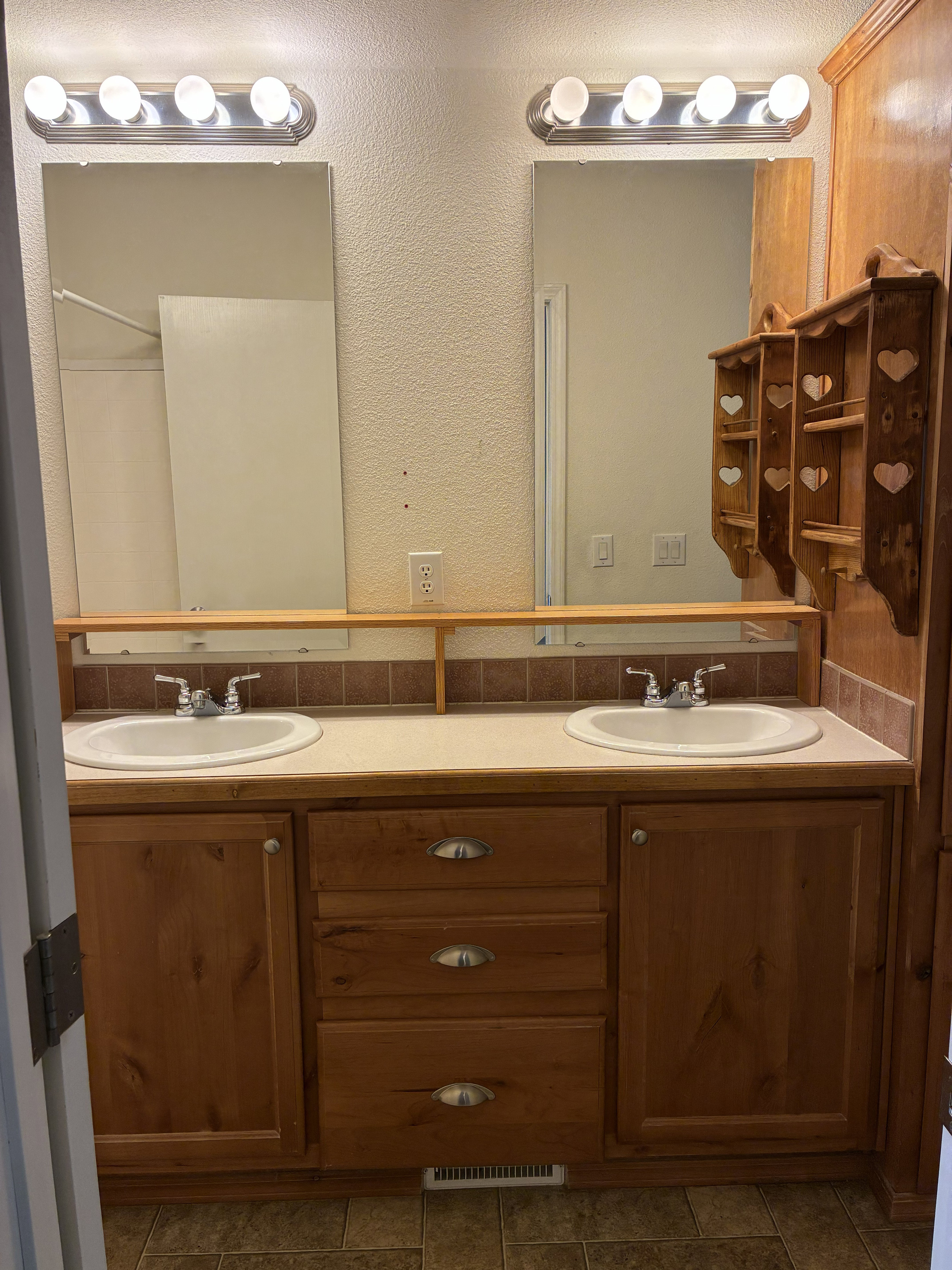 Double vanity with wood-finish cabinetry, integrated sinks, and individual mirrors