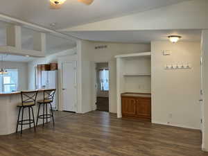Open-concept living area featuring LVP flooring, a breakfast bar, built-in shelving with cabinetry, and a coat rack