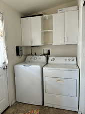 Dedicated laundry area featuring white upper cabinetry, open shelving