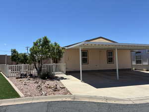 Exterior features a 3-car carport with concrete paving and beautiful landscaping