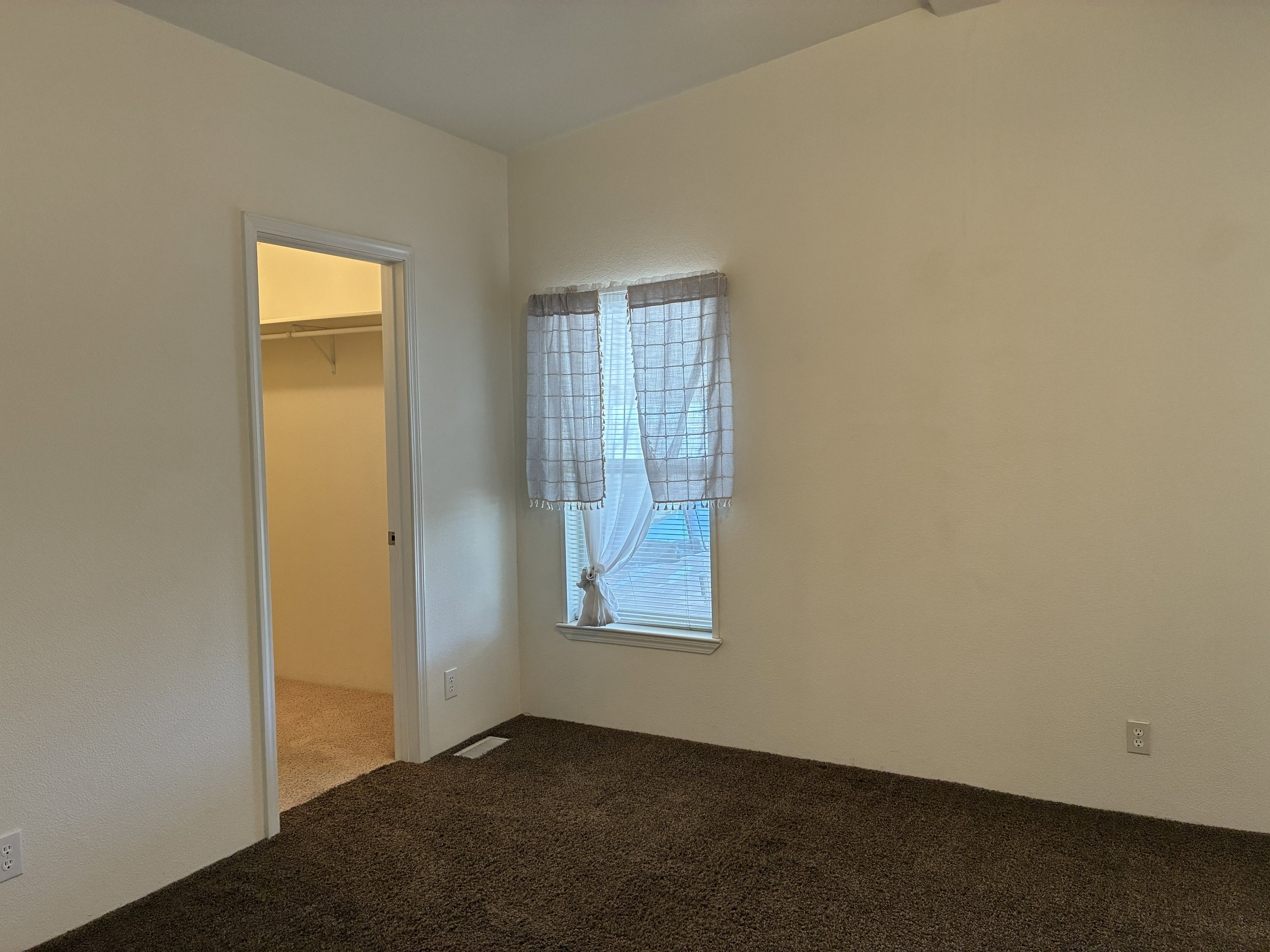 Primary bedroom with 2 windows with blinds, and a walk-in closet