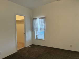 Primary bedroom with 2 windows with blinds, and a walk-in closet