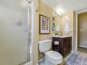 Bathroom featuring a frosted glass shower enclosure, a dark wood-finish vanity with a white countertop, a rectangular mirror, and overhead vanity lighting