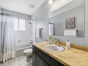 Bathroom featuring a single basin vanity with a wood-finish countertop, dark cabinetry, and a large wall-mounted mirror