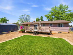 Rear exterior featuring a spacious wood deck, sliding glass door, and vinyl siding