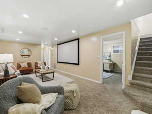 Entertainment space featuring a large projection screen, recessed lighting, wall-to-wall carpeting, and a visible doorway to an additional room