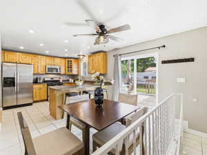 Open-concept kitchen featuring light wood cabinetry, stainless steel appliances, granite countertops, and tile flooring