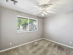 Carpeted room featuring a window with horizontal blinds, light gray wall paint, white baseboards, and a ceiling fan with integrated lighting