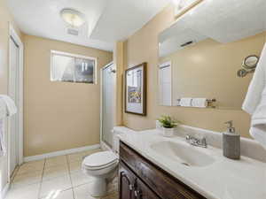 Bathroom featuring a vanity with an integrated sink and base cabinetry, a toilet, and a stand-up shower with a clear glass enclosure