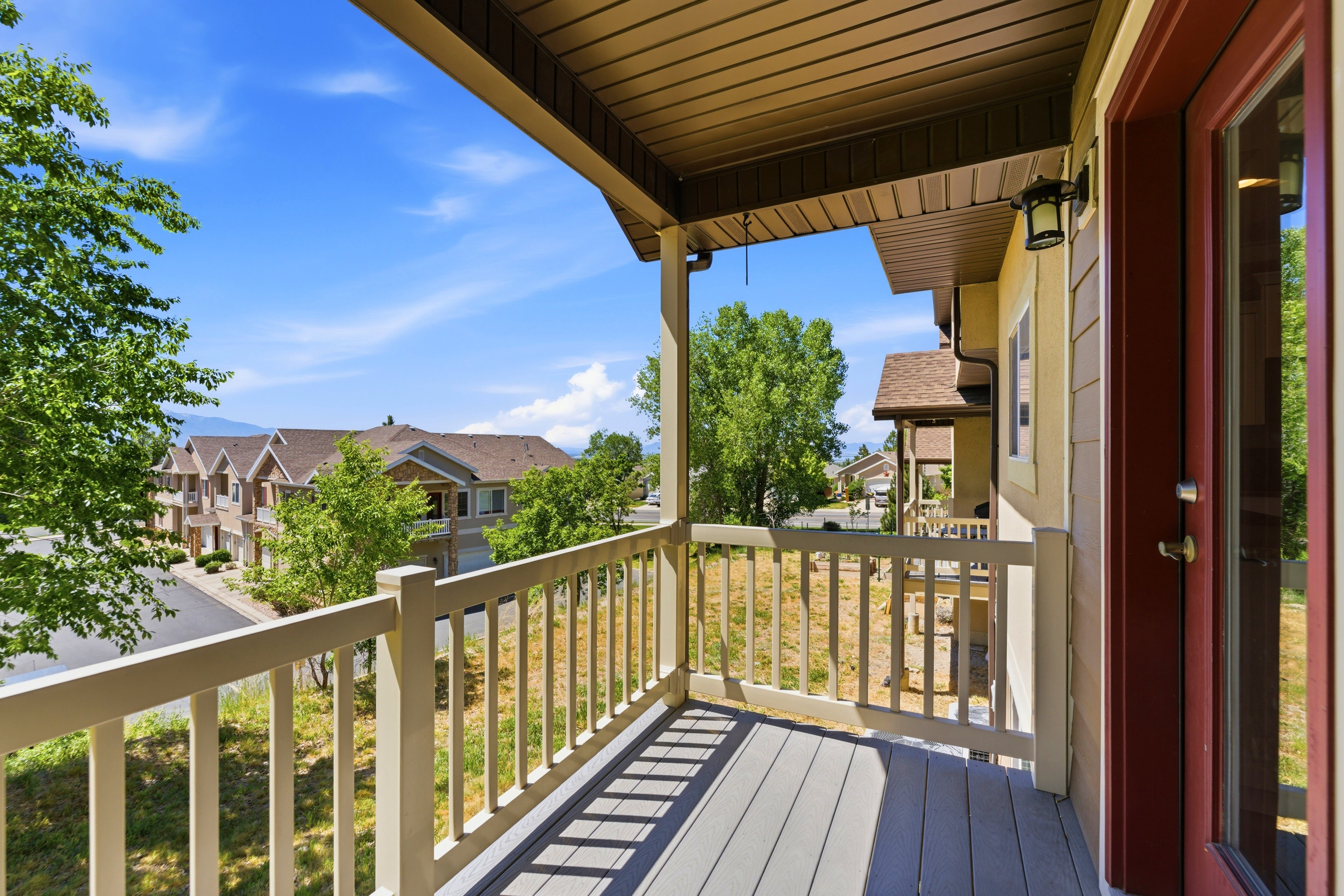 Covered balcony featuring composite decking and a painted wood railing