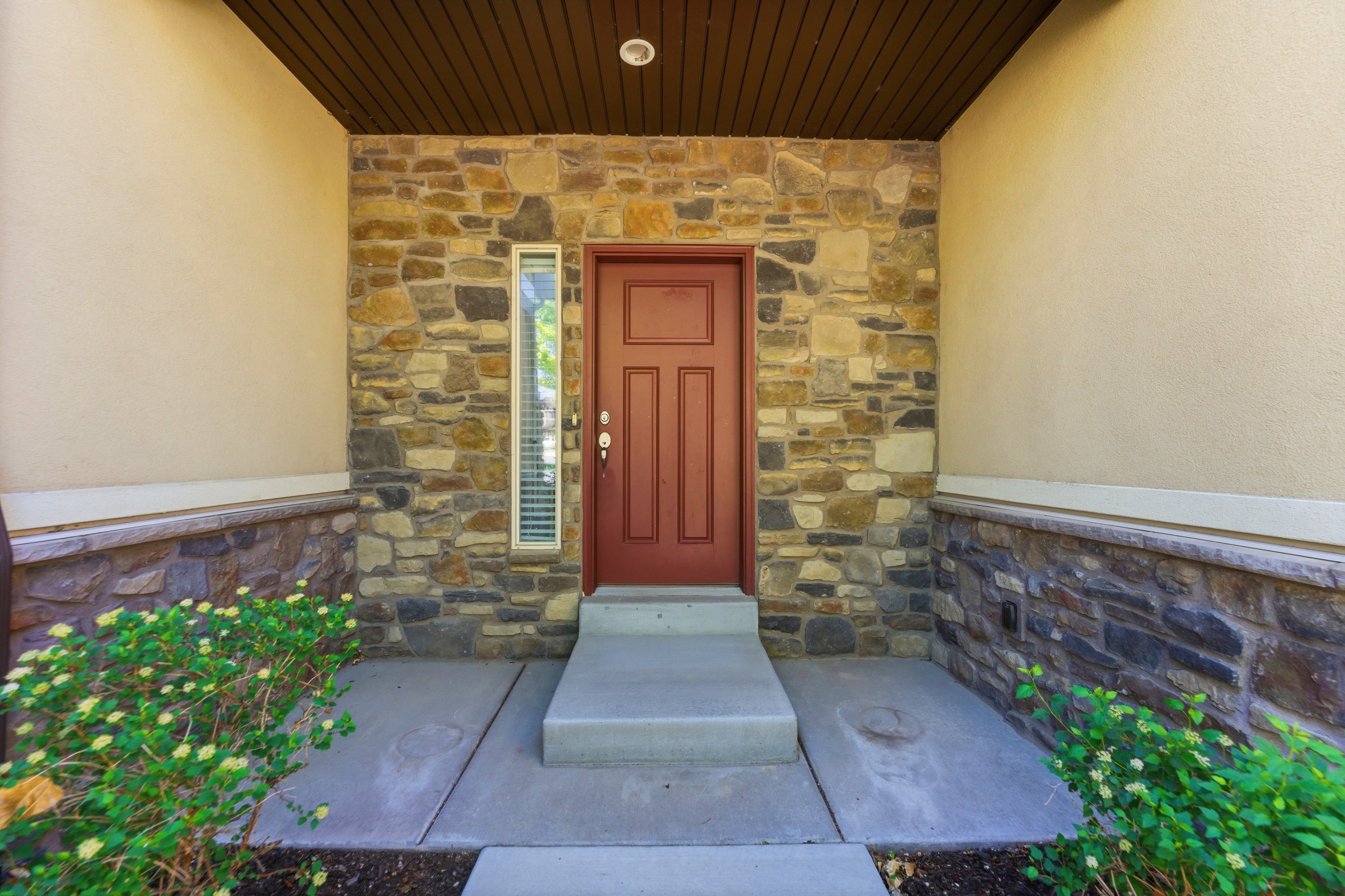 Entryway featuring a paneled door, vertical sidelight, and stone veneer facade