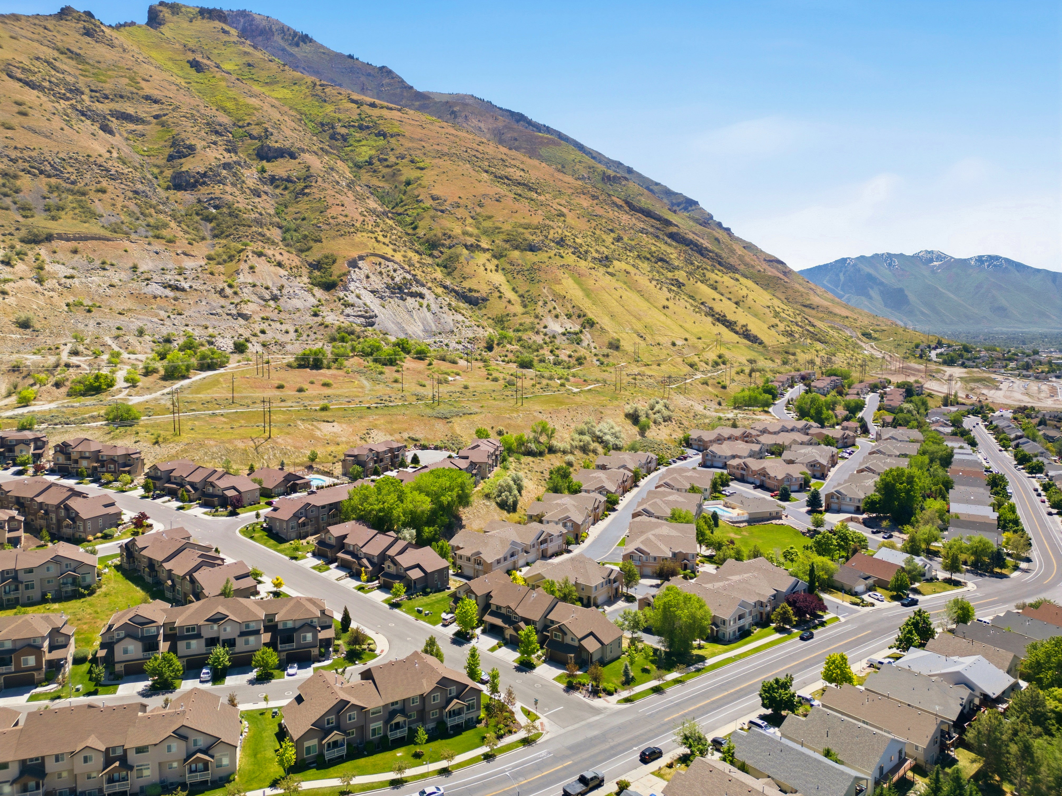 Residential development with a mountain backdrop, featuring paved roads, mature landscaping, and varied rooflines