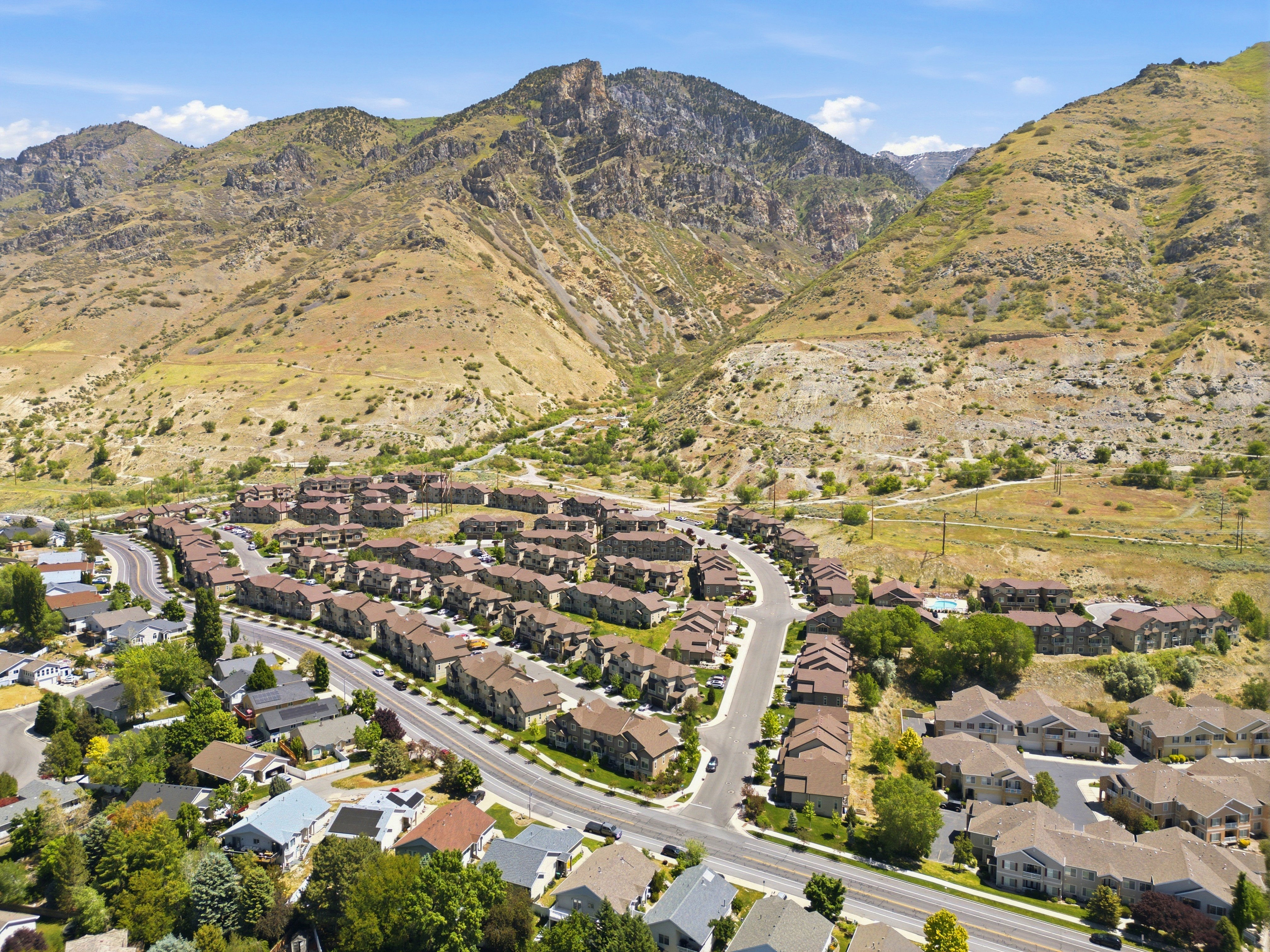 Aerial perspective showcasing a residential area nestled at the base of expansive, rugged mountains