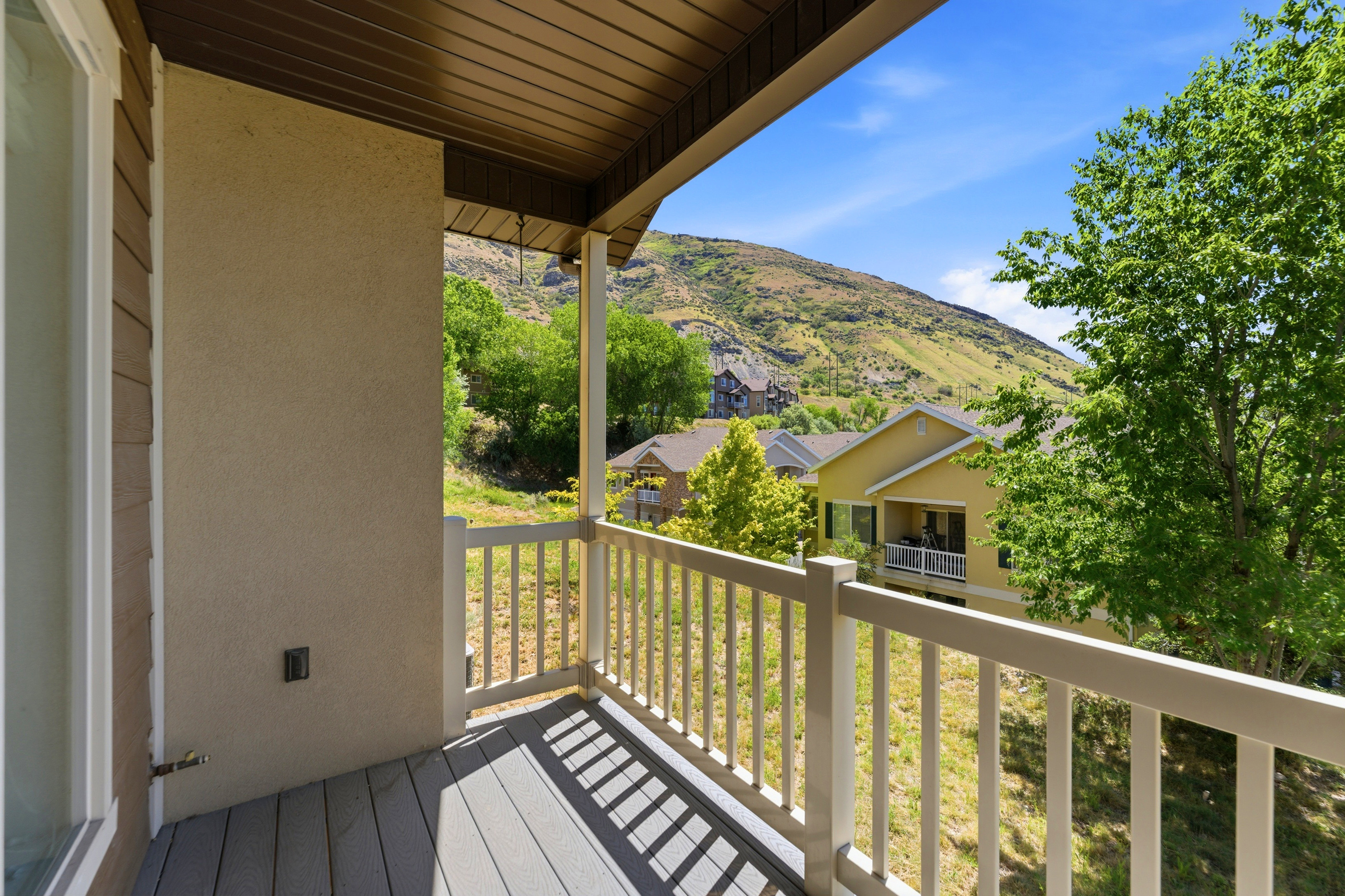 Private balcony featuring composite decking and a white railing overlooking a verdant hillside
