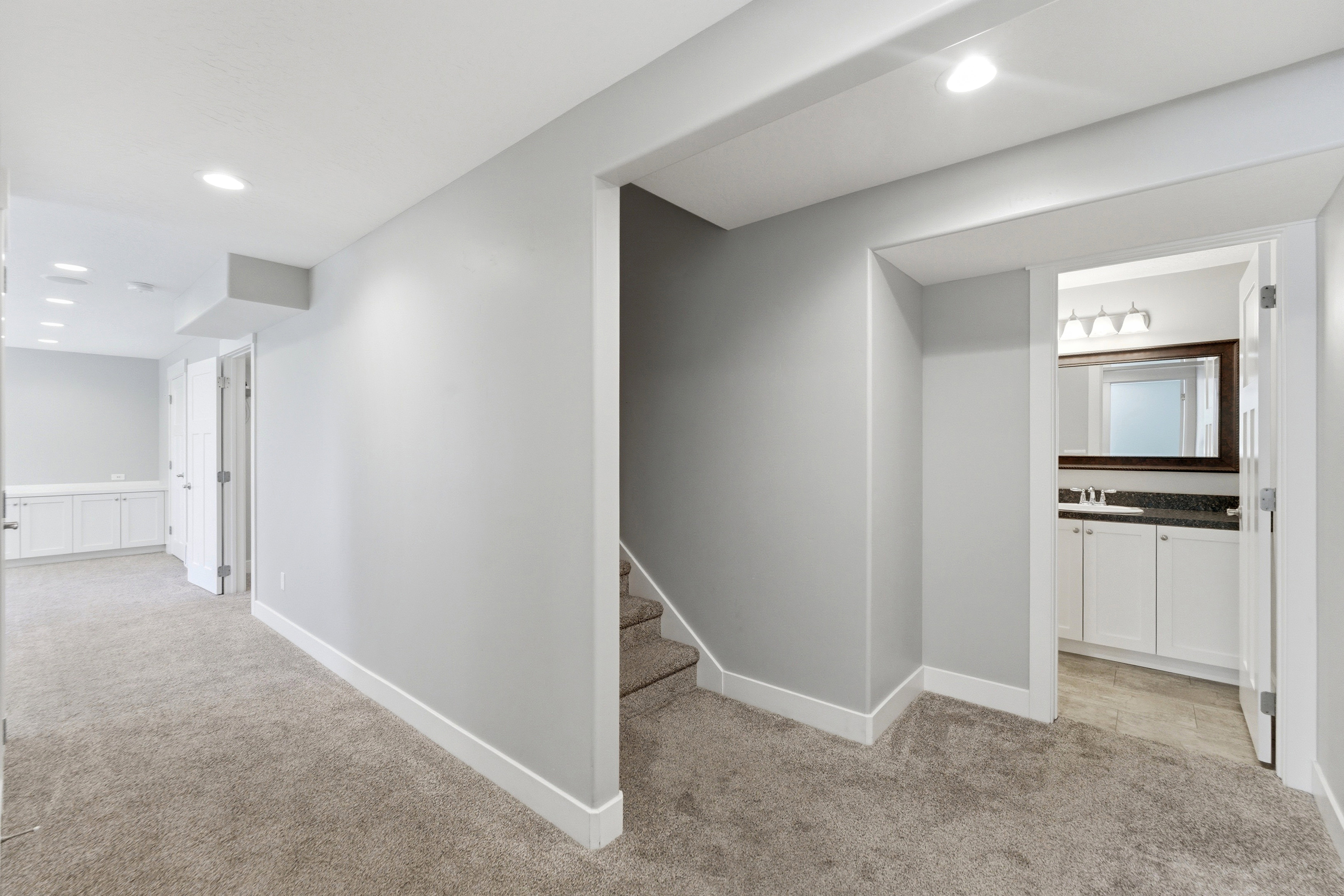 Carpeted hallway with light gray walls, white baseboards, and recessed lighting
