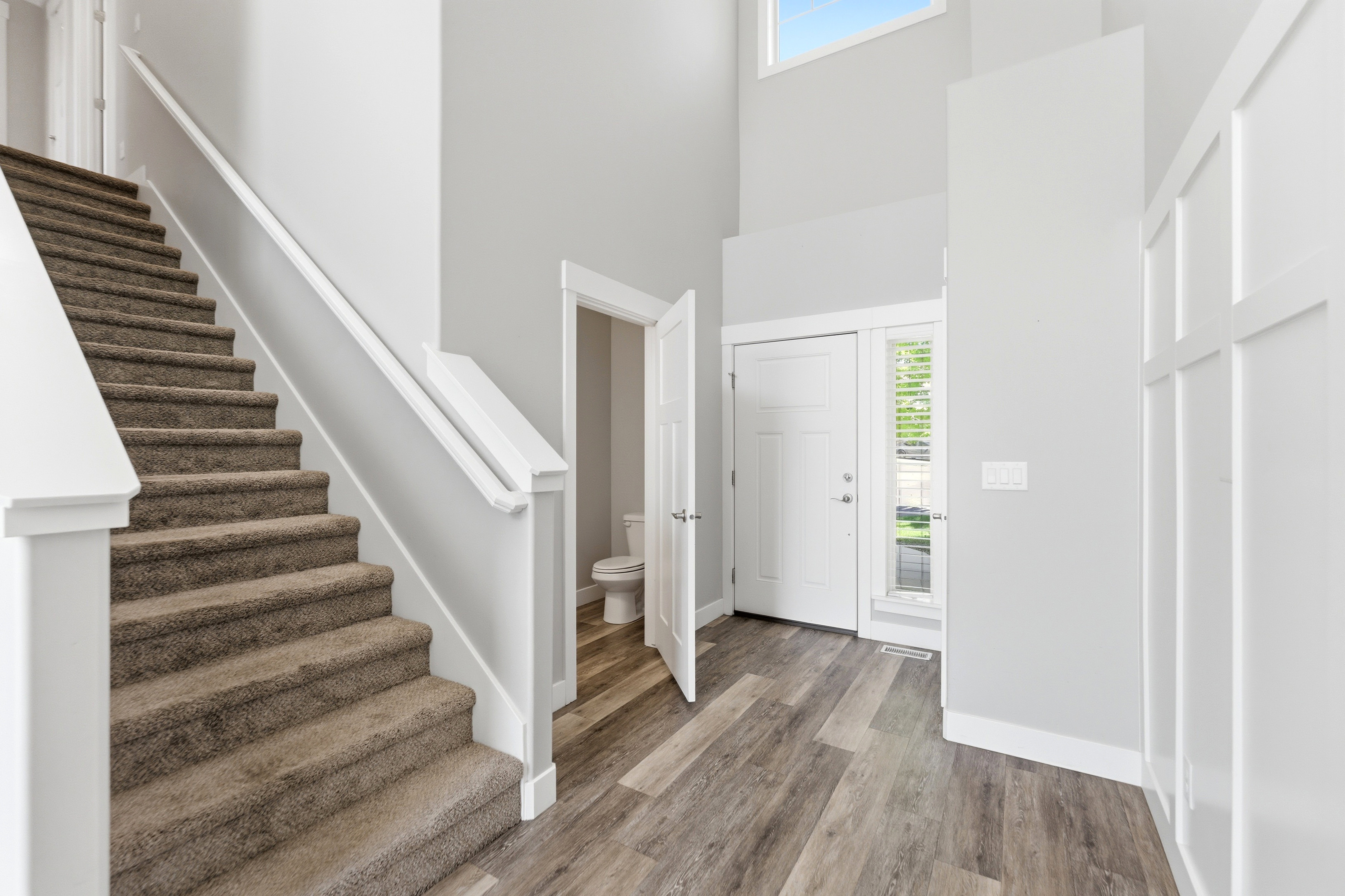 Two-story entryway with wood-finish flooring, board and batten wall detailing, and a carpeted staircase