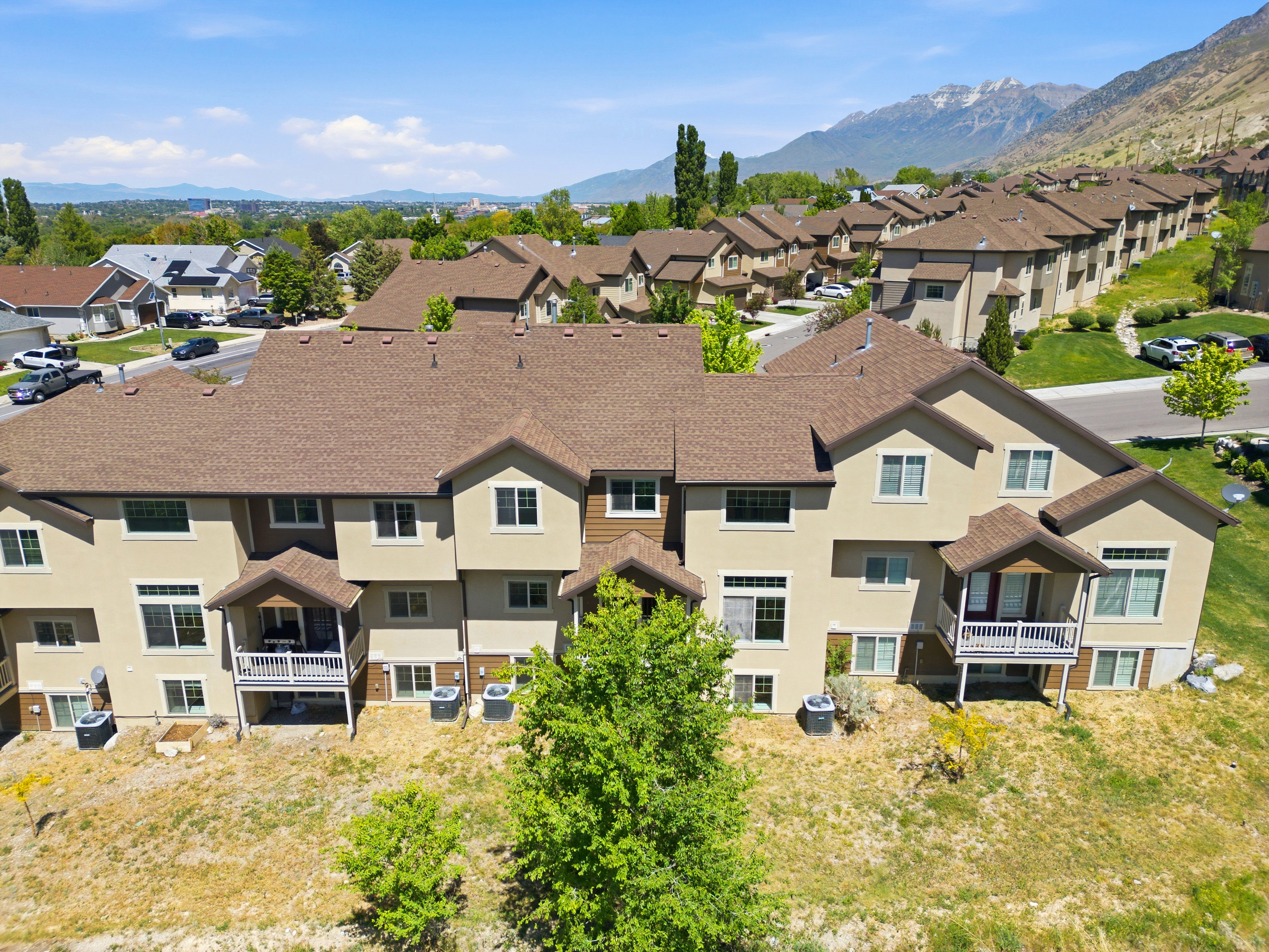 Townhome community featuring multi-story units with tan stucco exteriors and brown shingle roofs