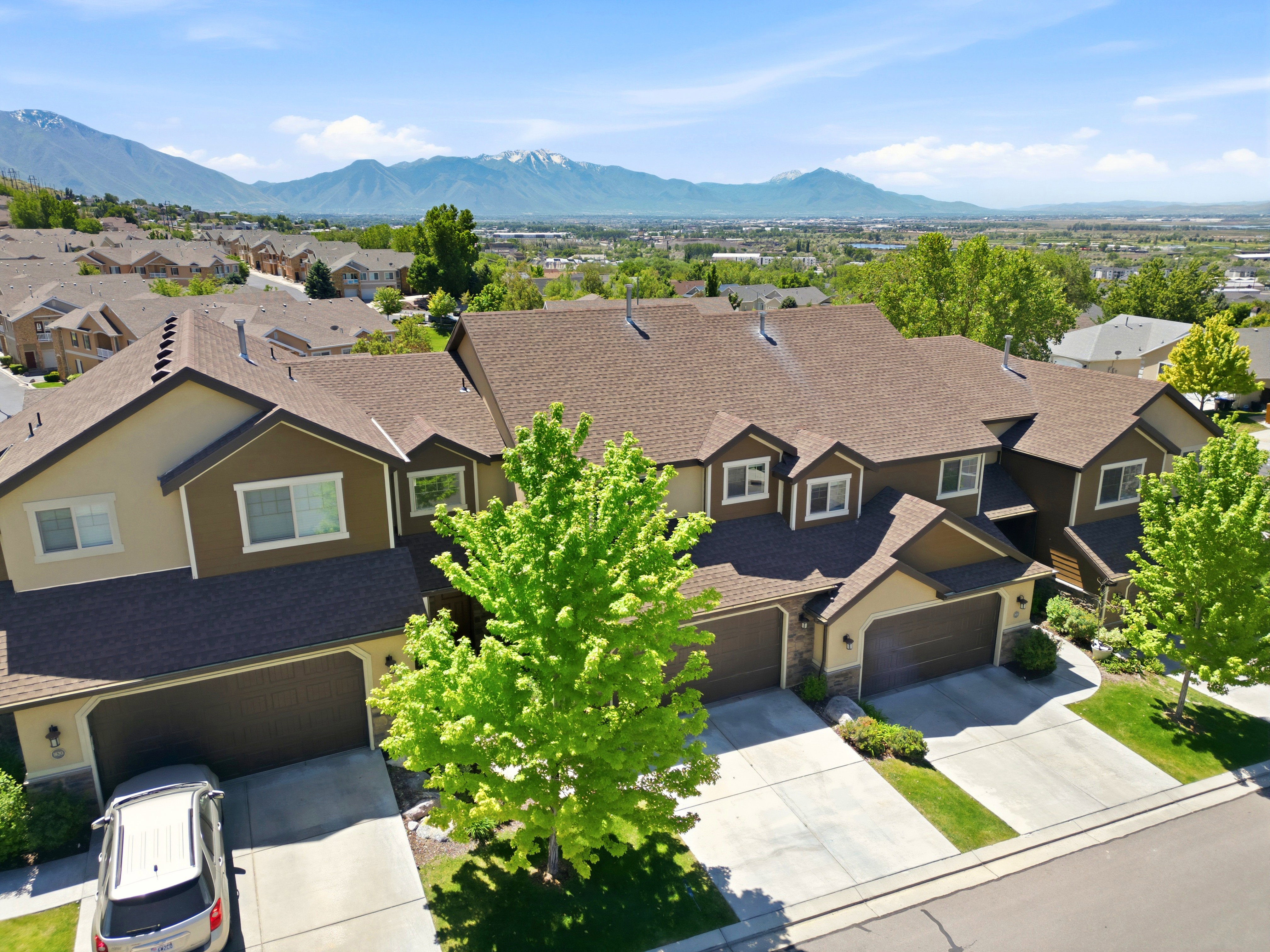 Multi-level townhome featuring a brown shingle roof and a two-car garage