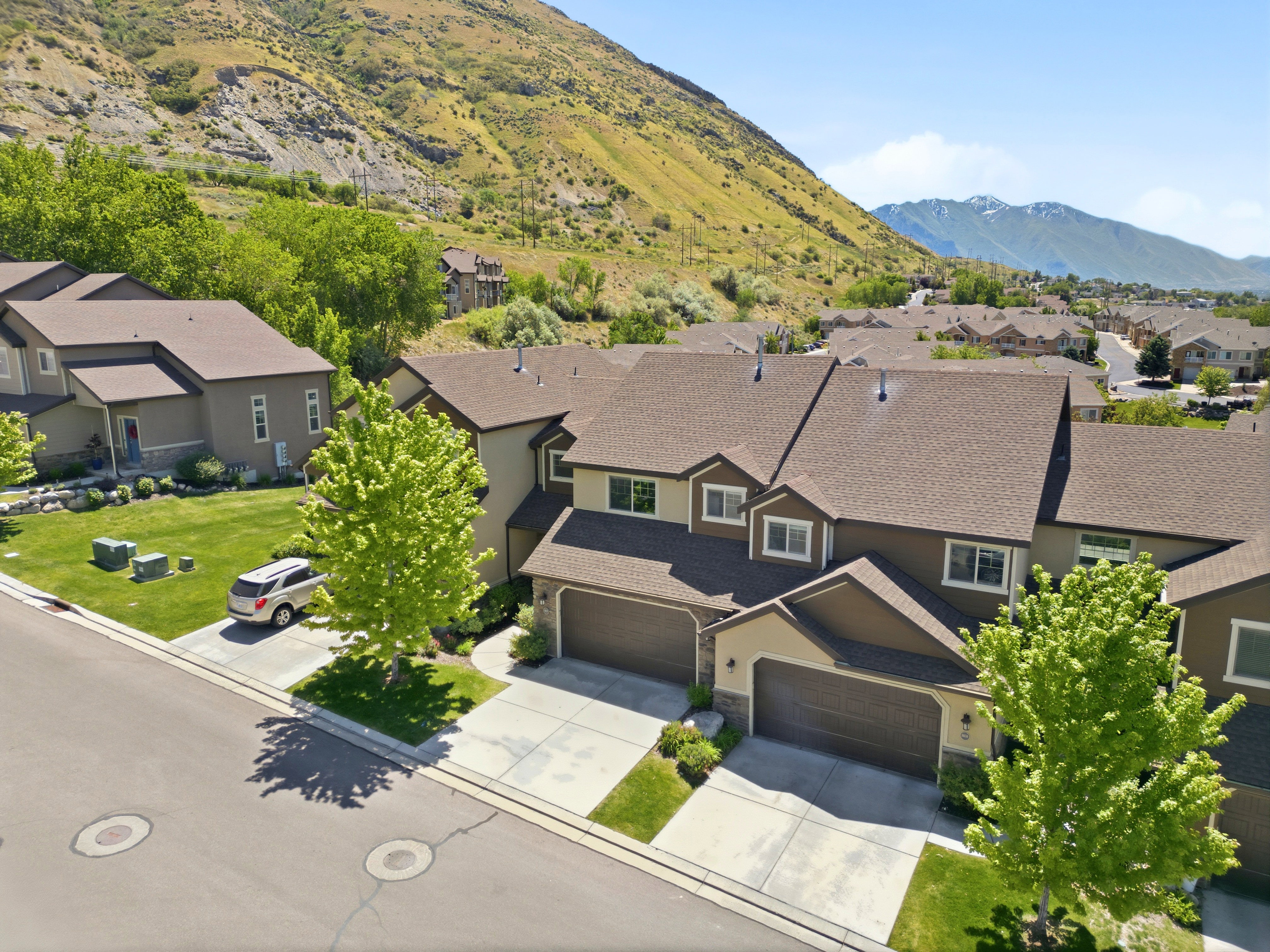 Contemporary townhome-style residences featuring attached garages, paved driveways, and surrounding green spaces