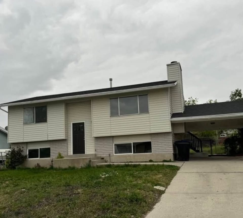 Split foyer home featuring a front lawn, a chimney, an attached carport, and concrete driveway