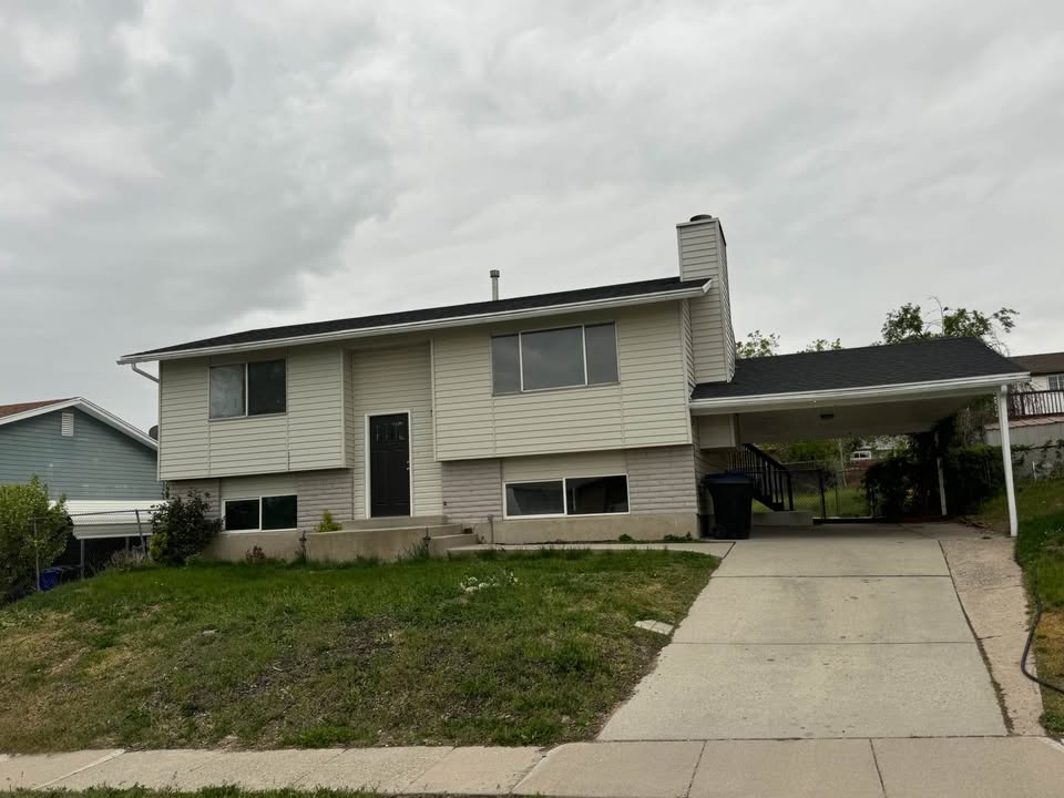 Split foyer home featuring a front lawn, a carport, a chimney, and driveway