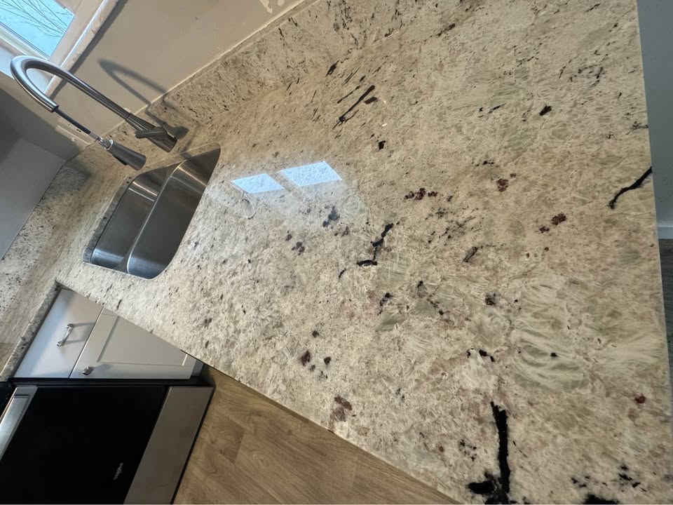 Kitchen view of light stone counters, wood finished floors, and white cabinetry