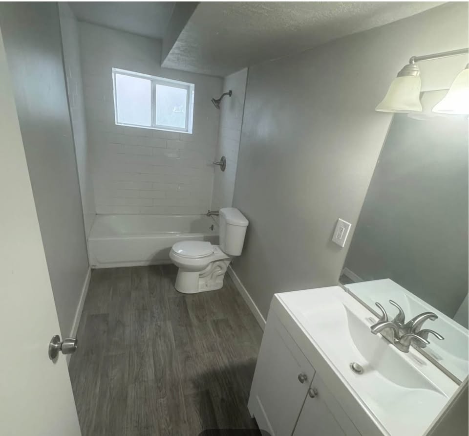 Full bathroom featuring vanity, dark wood finished floors, washtub / shower combination, and a textured ceiling
