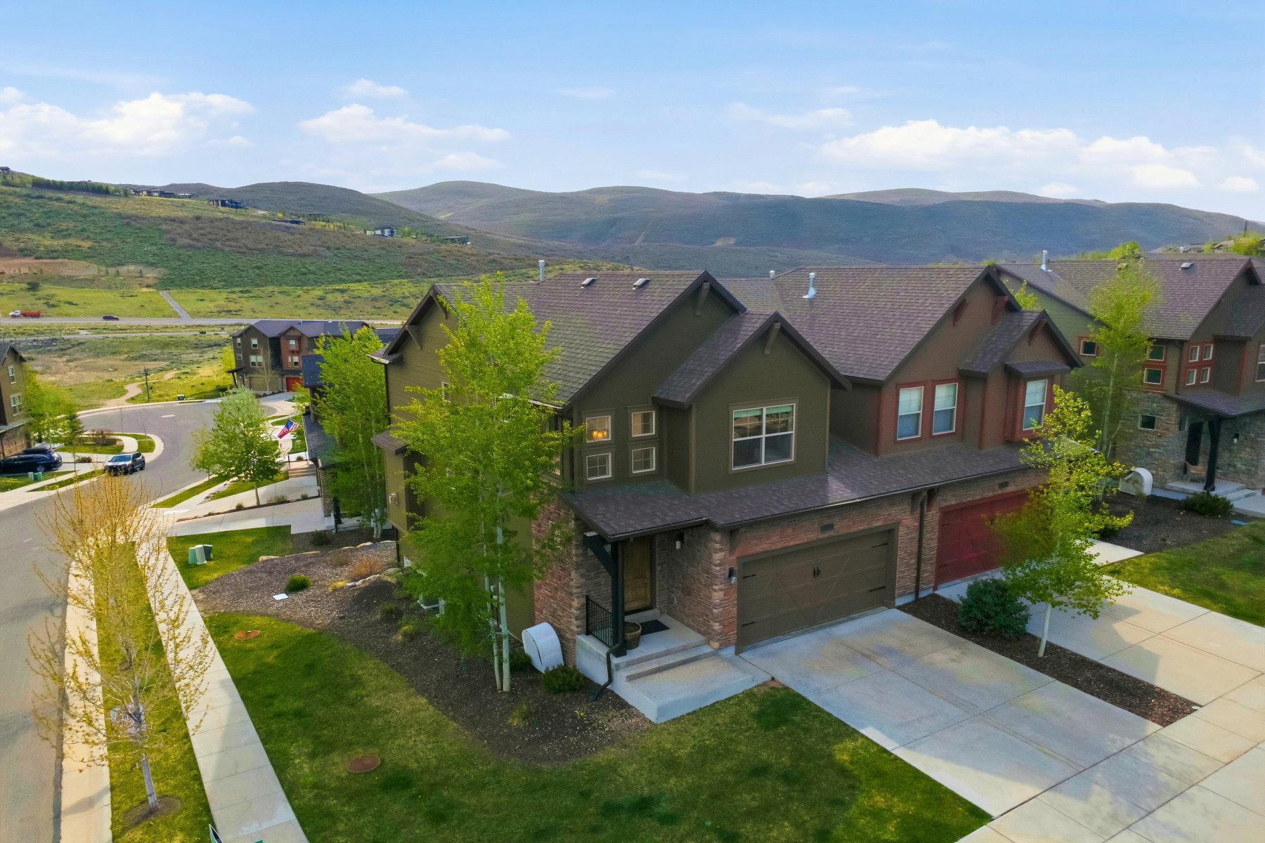 Contemporary two-story residence with a multi-tone exterior, featuring a stone and brick facade, an attached two-car garage, and a concrete driveway