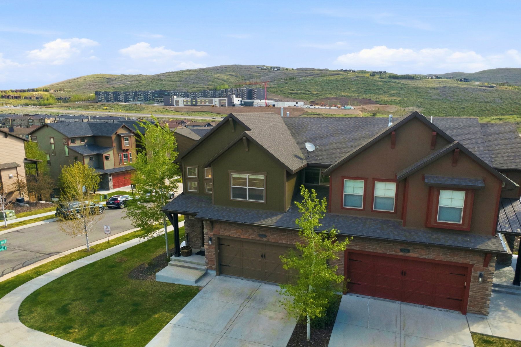 Contemporary brown and green multi-story home featuring brick and stone accents