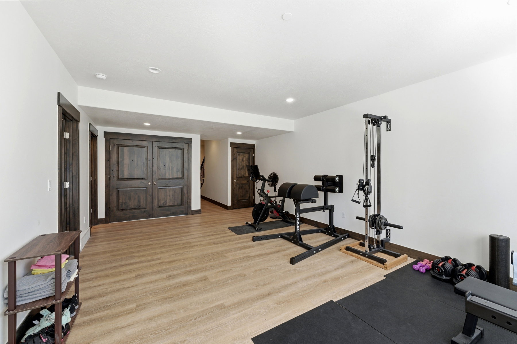 Versatile lower-level space featuring wood-finish flooring, recessed lighting, and dark wood trim