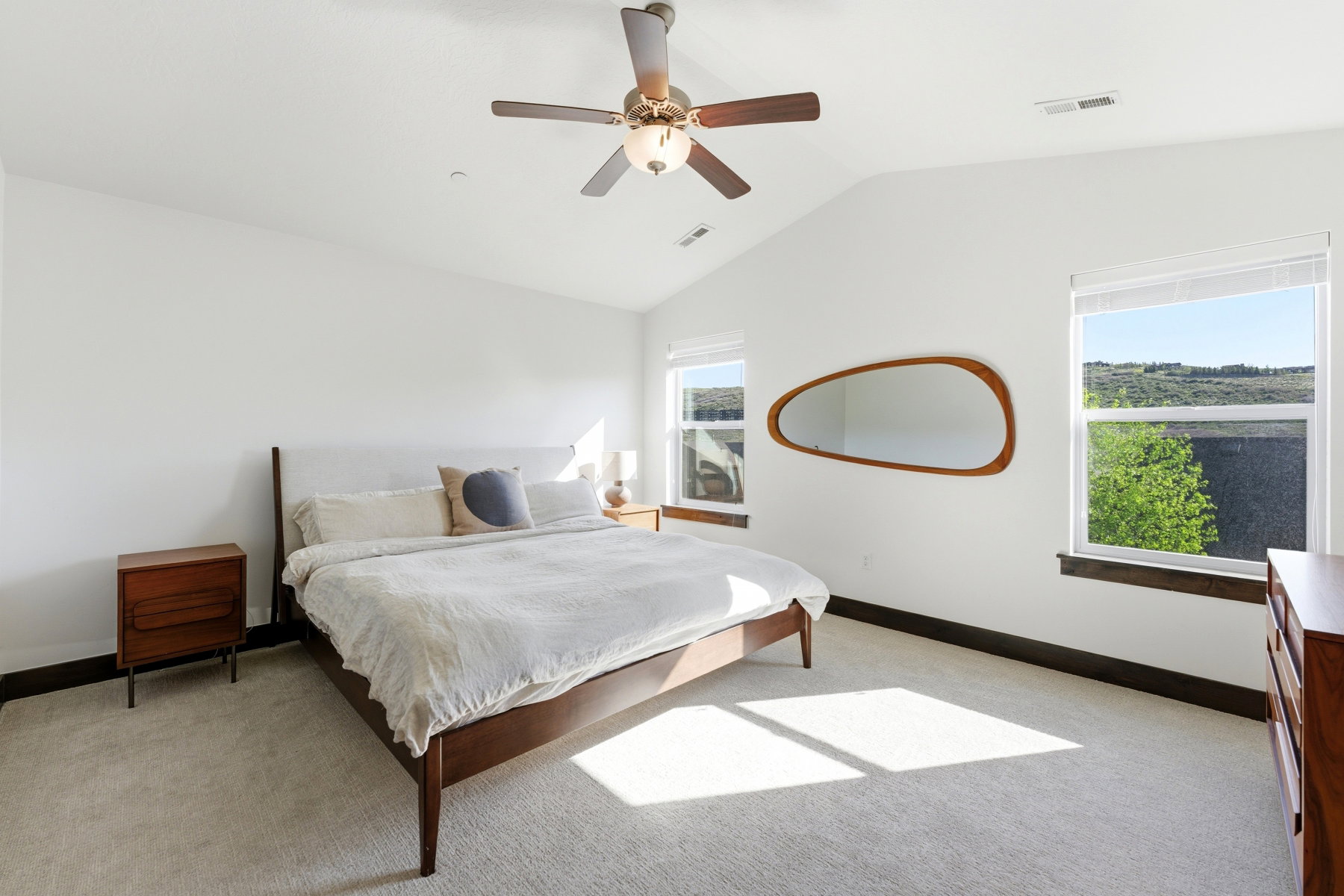 Vaulted ceiling bedroom with light-toned carpet flooring