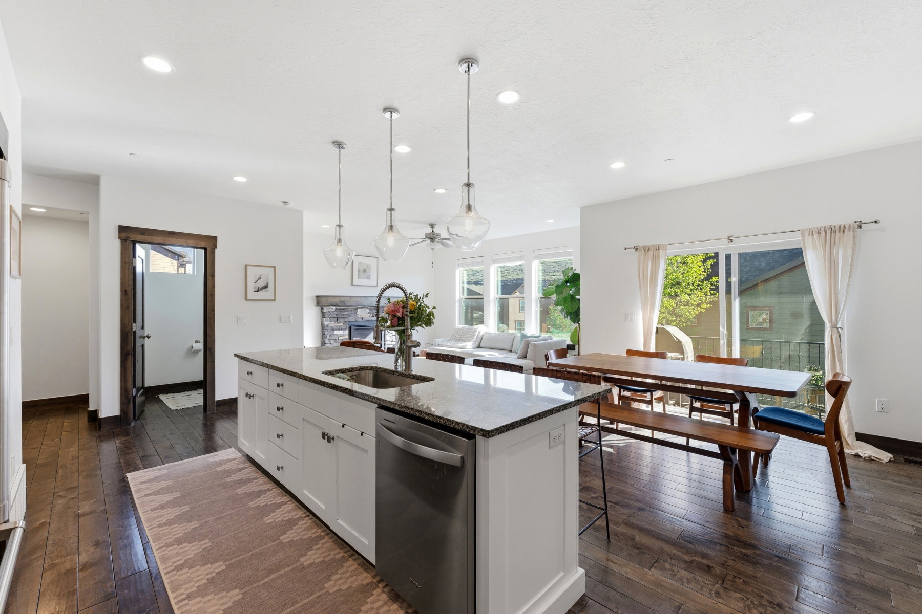 Spacious kitchen featuring a large island with a stainless steel sink and dishwasher, pendant lighting, recessed lighting, and rich wood-finish flooring