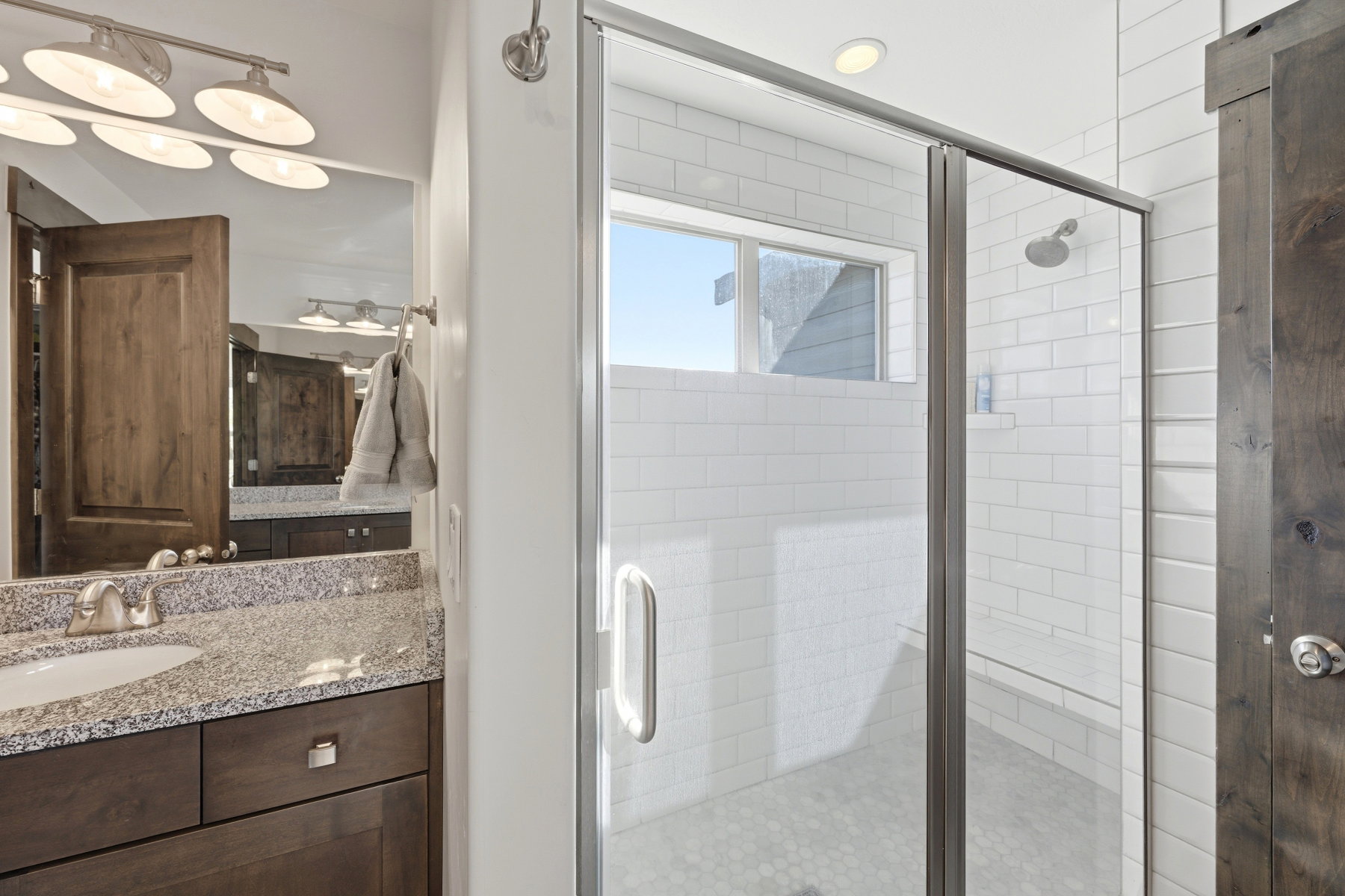 Shower enclosure with white subway tile surround and hexagon tile flooring, featuring a clear glass door