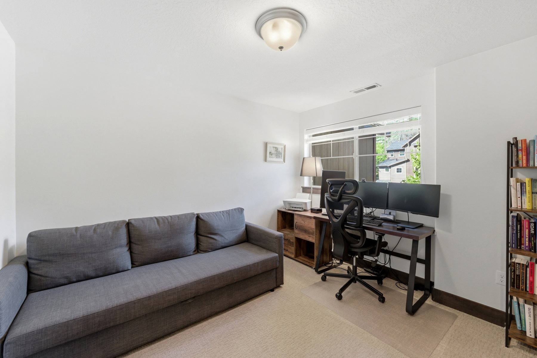 Carpeted room featuring a large window, a ceiling-mounted light fixture, and white wall finishes