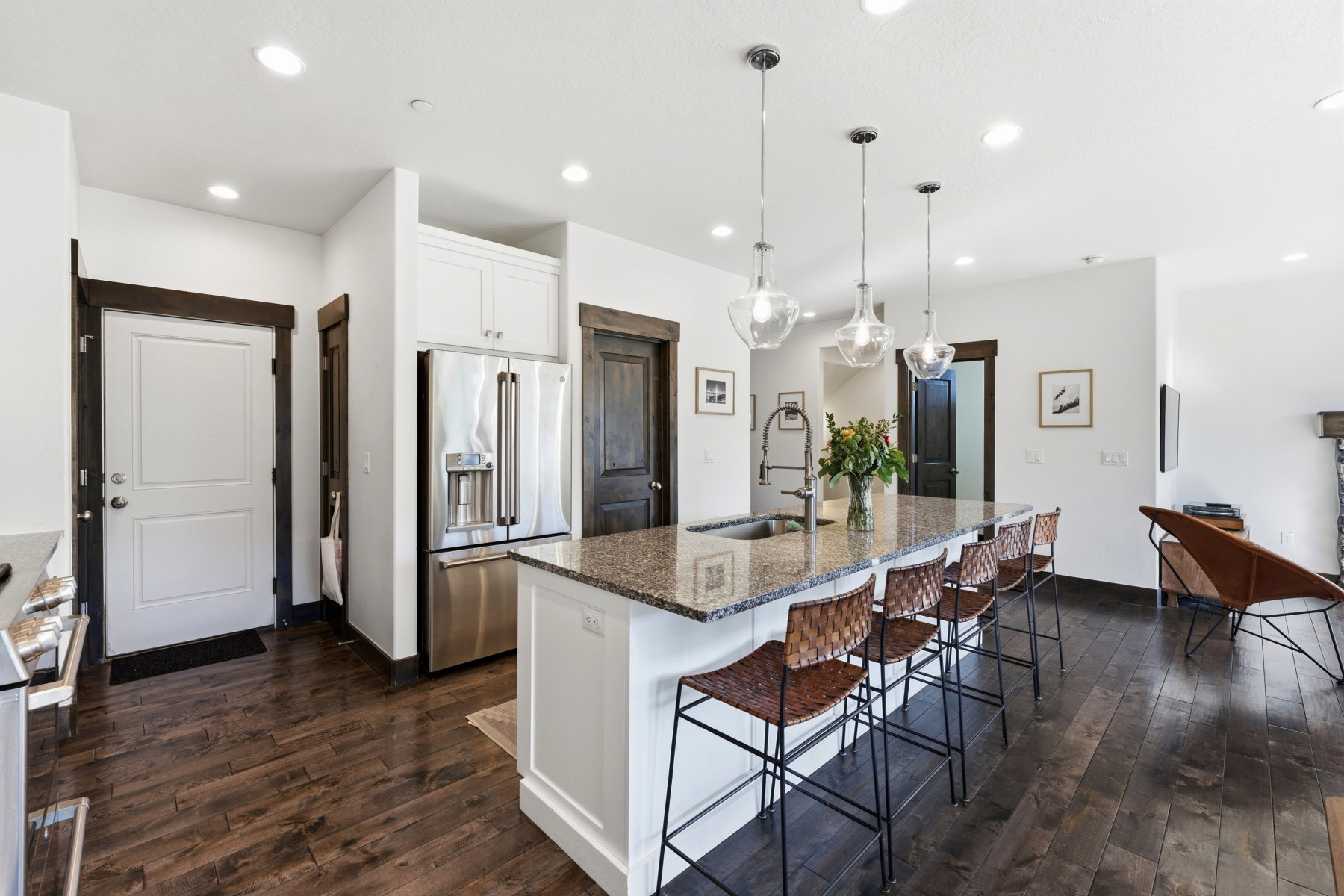 Open-concept kitchen featuring a large island with seating, granite countertops, stainless steel appliances, and wood-finish flooring