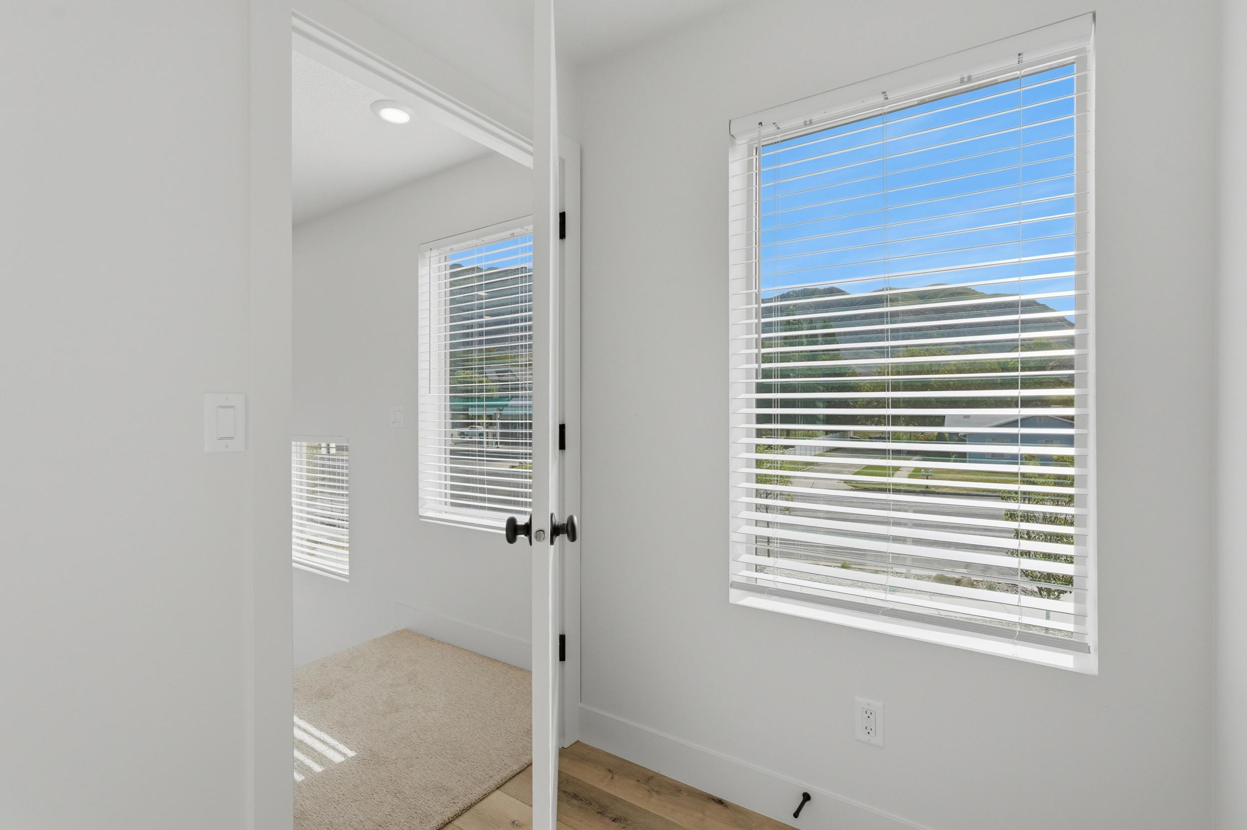 Bright room featuring mountain scenery, window blinds, light-colored walls, recessed lighting, and wood-finish flooring