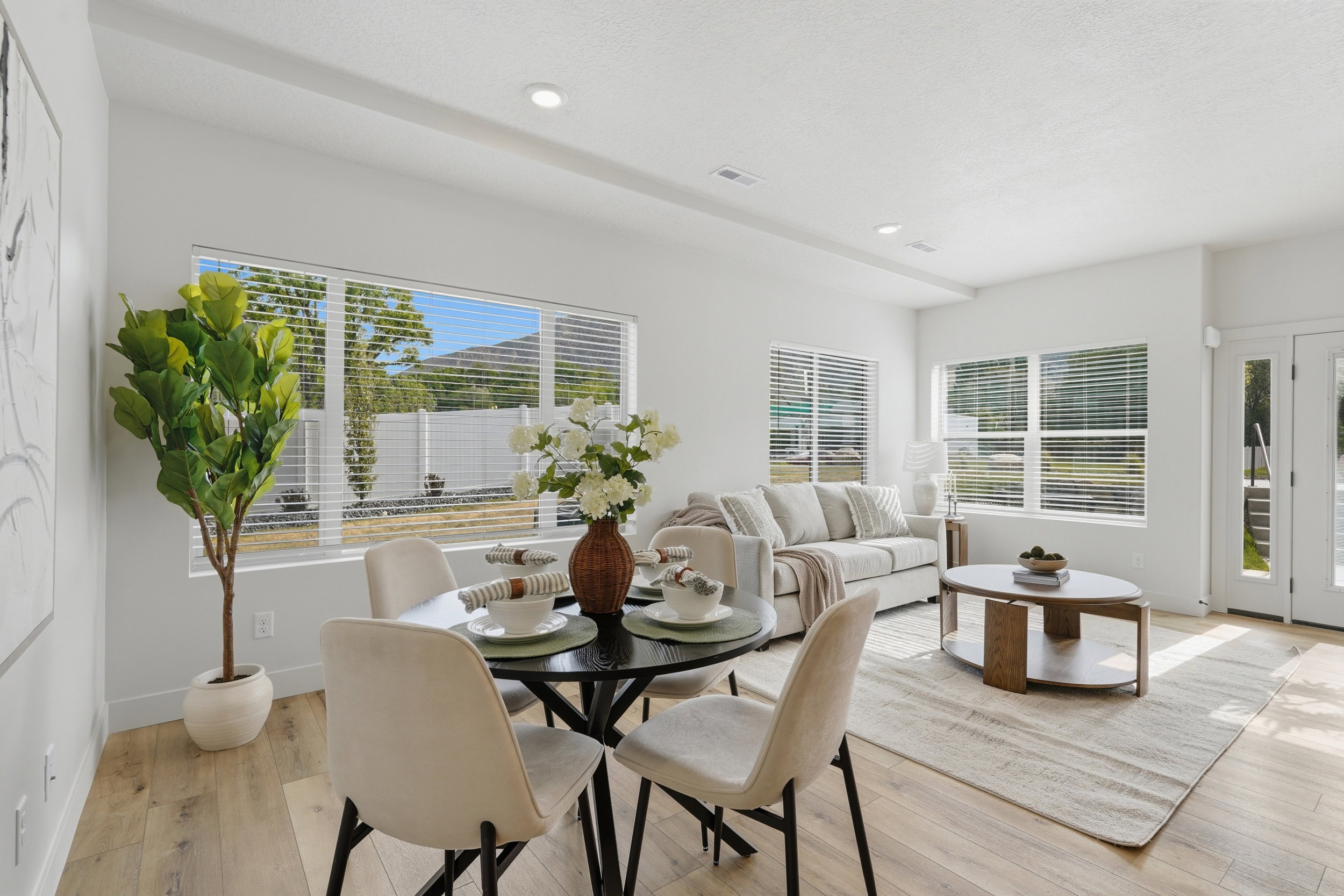 Open-concept living area featuring wood-finish flooring, recessed lighting, and expansive windows with horizontal blinds