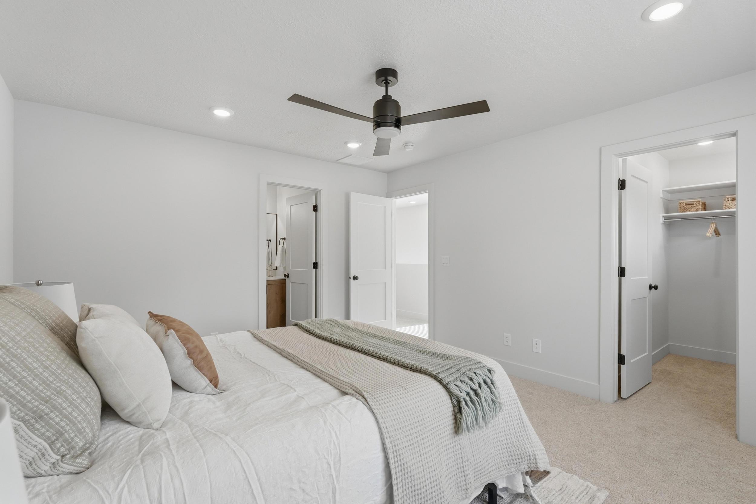 Bright bedroom featuring neutral-toned carpet, recessed lighting, and a dark-toned ceiling fan