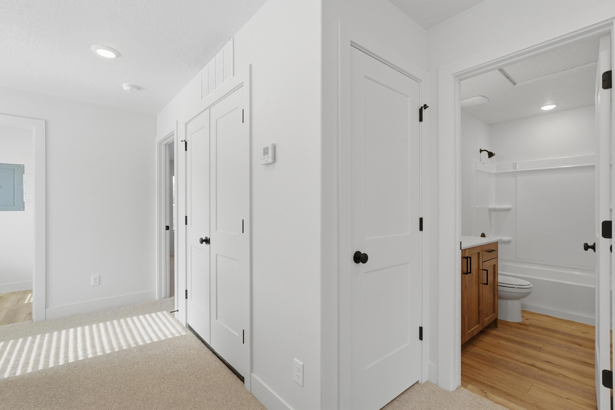 Hallway featuring recessed lighting, white doors with matte black hardware, and neutral carpet